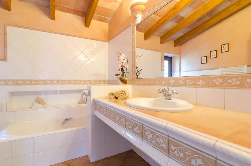 Un baño alicatado con bañera y un largo lavabo con una pila.