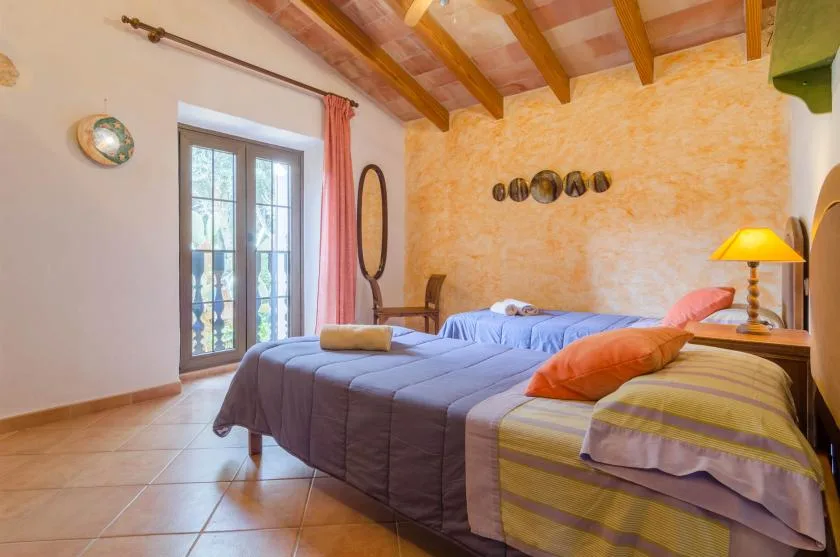 Un dormitorio con dos camas, ropa de cama colorida y vigas de madera a la vista.