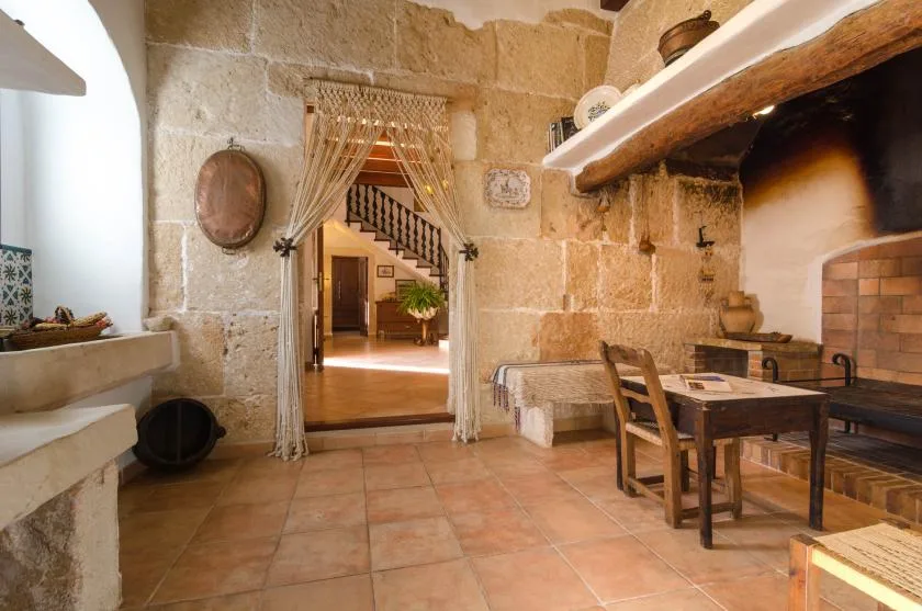 Un comedor rústico de piedra con una mesa de madera junto a una gran chimenea.