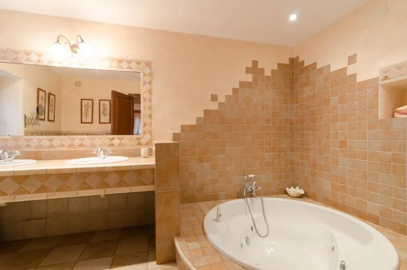 Un baño con bañera, paredes de azulejos y un lavabo bajo un espejo.