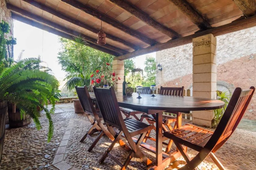 Un comedor exterior cubierto con una mesa larga y asientos de madera.