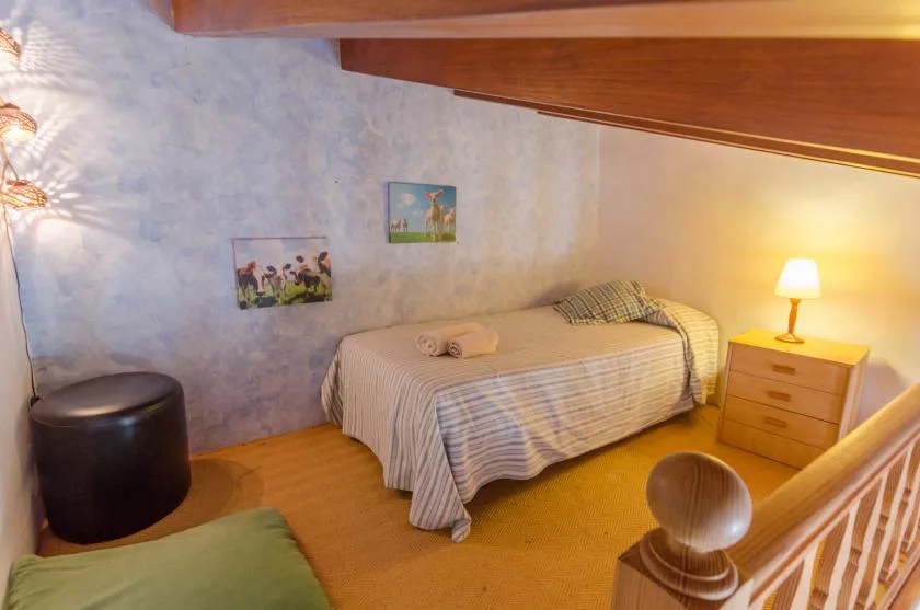Un dormitorio con una cama individual, una mesita de noche y luz cálida.