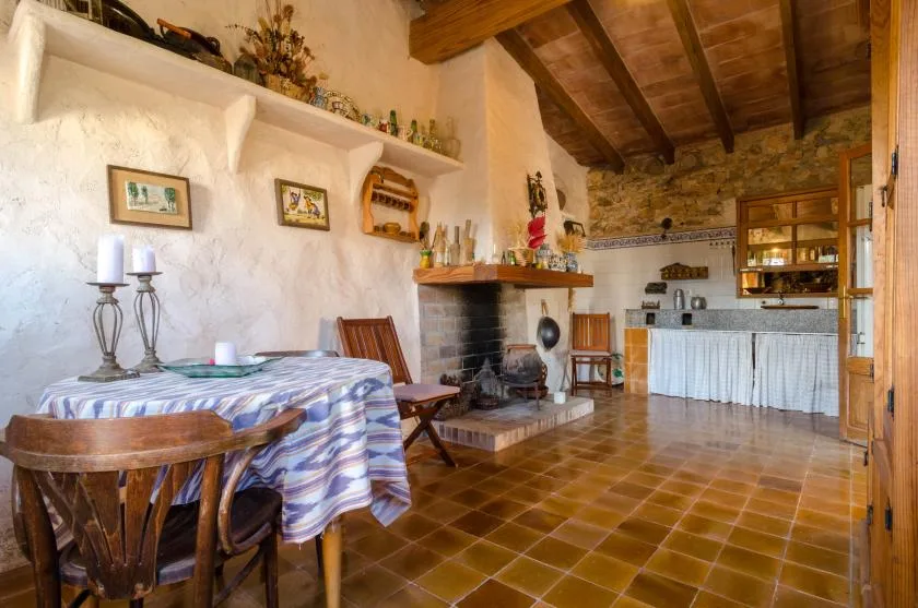 Una cocina y comedor rústicos con una mesa, una chimenea y un techo de madera.