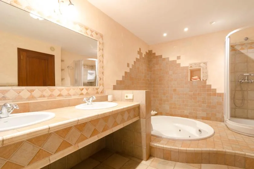 Un baño alicatado con un tocador largo, espejo, bañera y ducha.