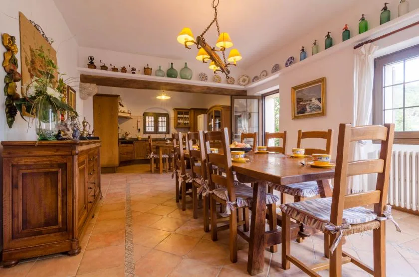 Un comedor con una mesa larga de madera y sillas junto a grandes ventanas.