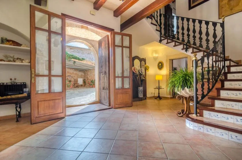 Un recibidor con puertas de madera abiertas y una escalera junto a la pared.