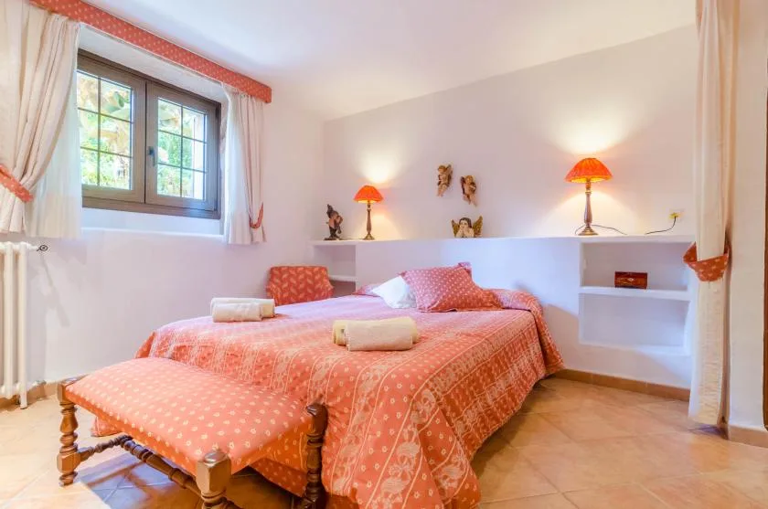 Un dormitorio con una cama doble, ropa de cama estampada y una ventana con cortinas.