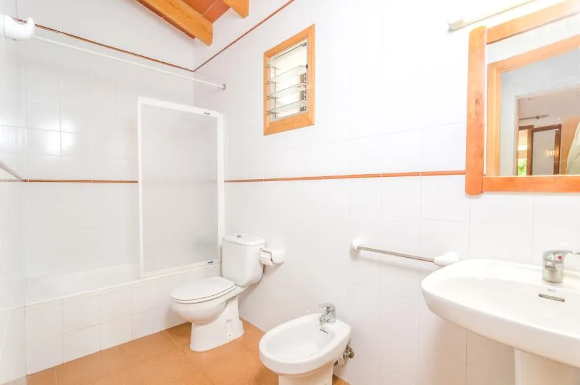 Un baño luminoso con ducha, inodoro, bidé y lavabo.