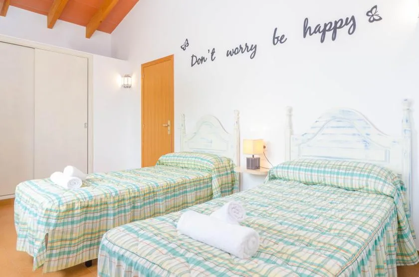 Un dormitorio luminoso con dos camas vestidas con ropa de cuadros a juego.