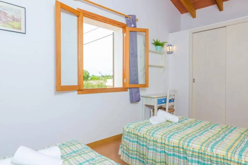 Un dormitorio con dos camas, una ventana y un escritorio pequeño.