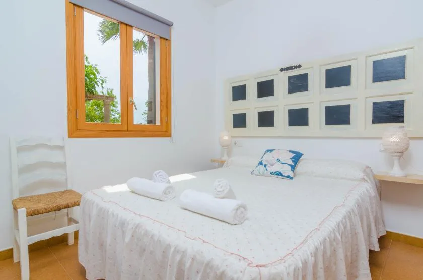 Un dormitorio luminoso con una cama grande bajo una fila de ventanas pequeñas.