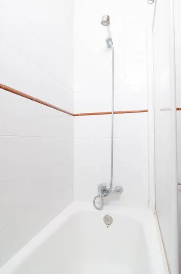 Una bañera blanca con ducha y un cabezal fijado a la pared.