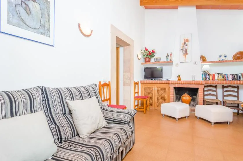 Una sala de estar con asientos a rayas, una chimenea y dos otomanas tapizadas.