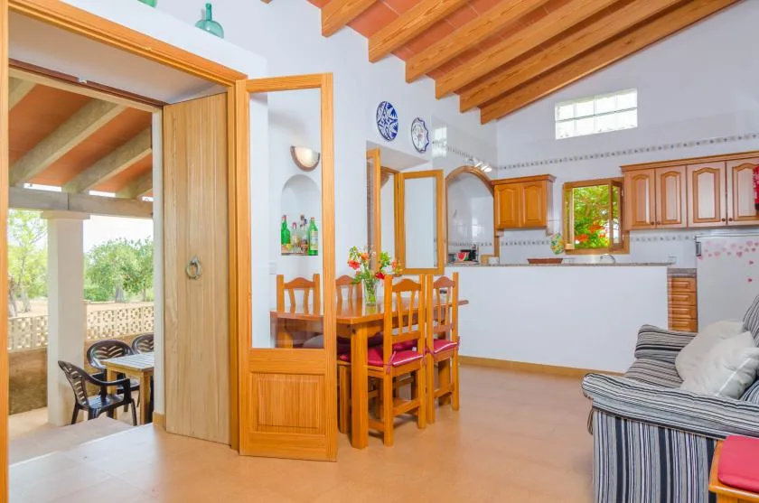 Un comedor se abre a una cocina, con asientos de madera y vigas vistas.