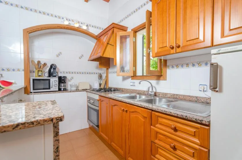 Una cocina luminosa con gabinetes de madera, una encimera y un fregadero de acero inoxidable.