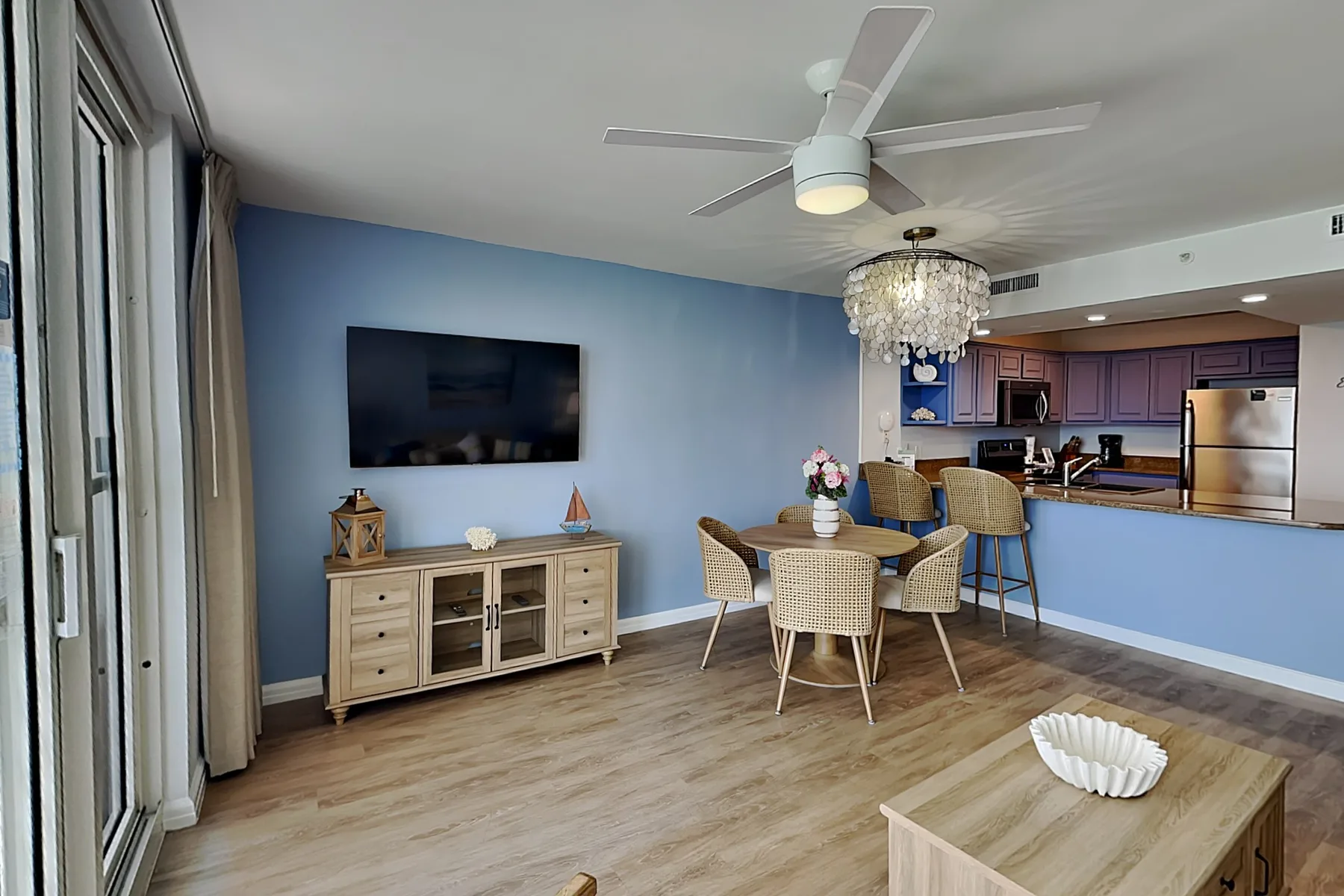 An open dining and kitchen area with a table, counter, and wall-mounted television.