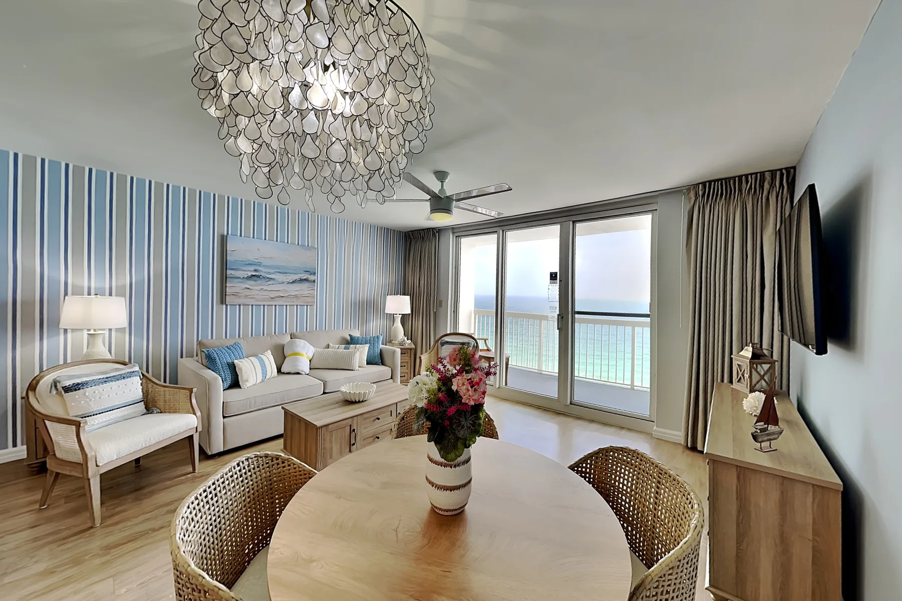 A bright living room with seating beside glass doors overlooking the water.