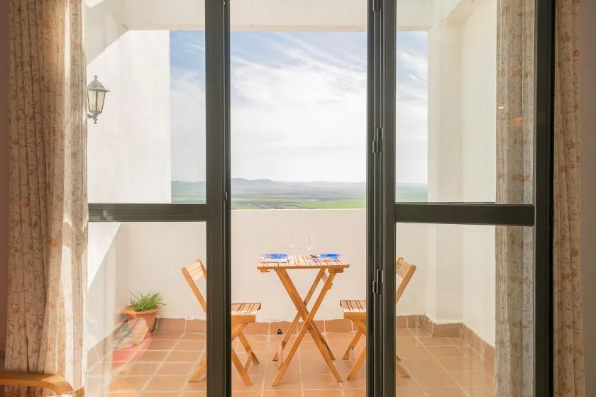 A bright balcony with a small table and chairs overlooking the landscape.