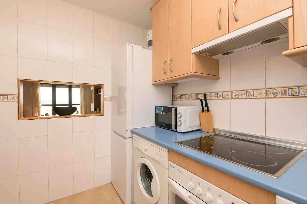 Una cocina alicatada con encimera azul y electrodomésticos.