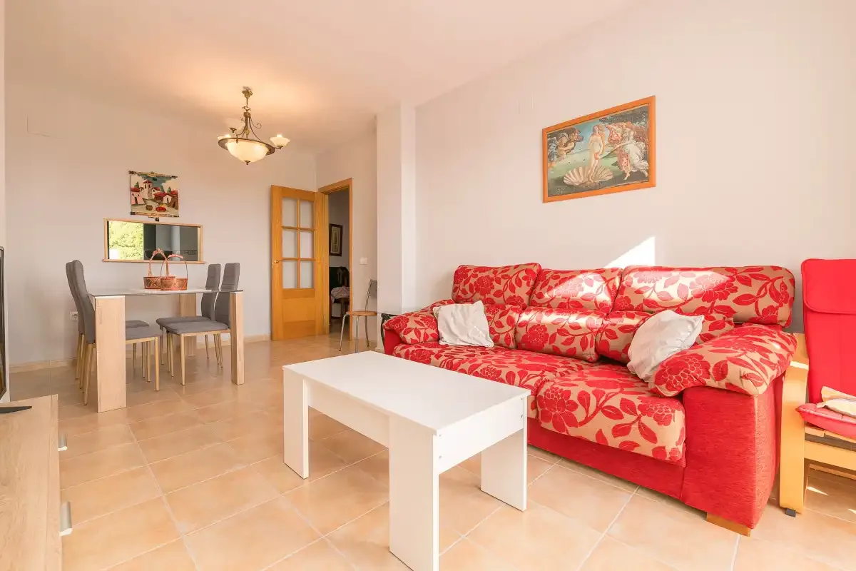 Sala de estar y comedor con asientos rojos y una mesa de centro blanca.