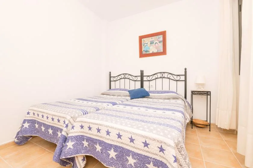 Un dormitorio con una cama de estructura metálica y una colcha estampada azul y blanca.
