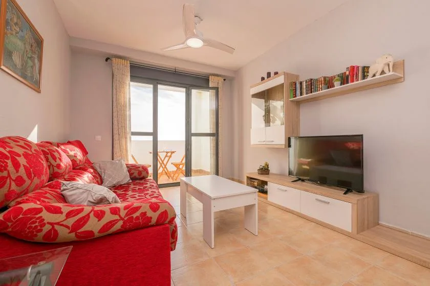A bright living room with red seating, a coffee table, and a television.