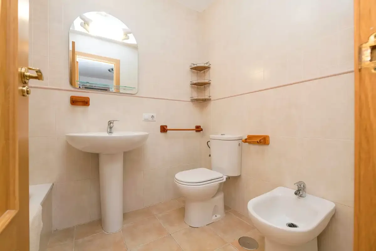 Un baño luminoso con lavabo, inodoro y bidé.