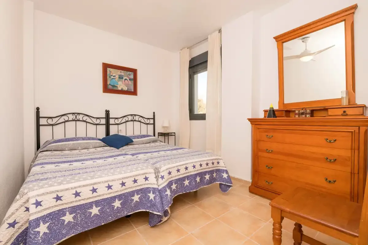 Un dormitorio con una cama doble y una cómoda de madera con espejo.