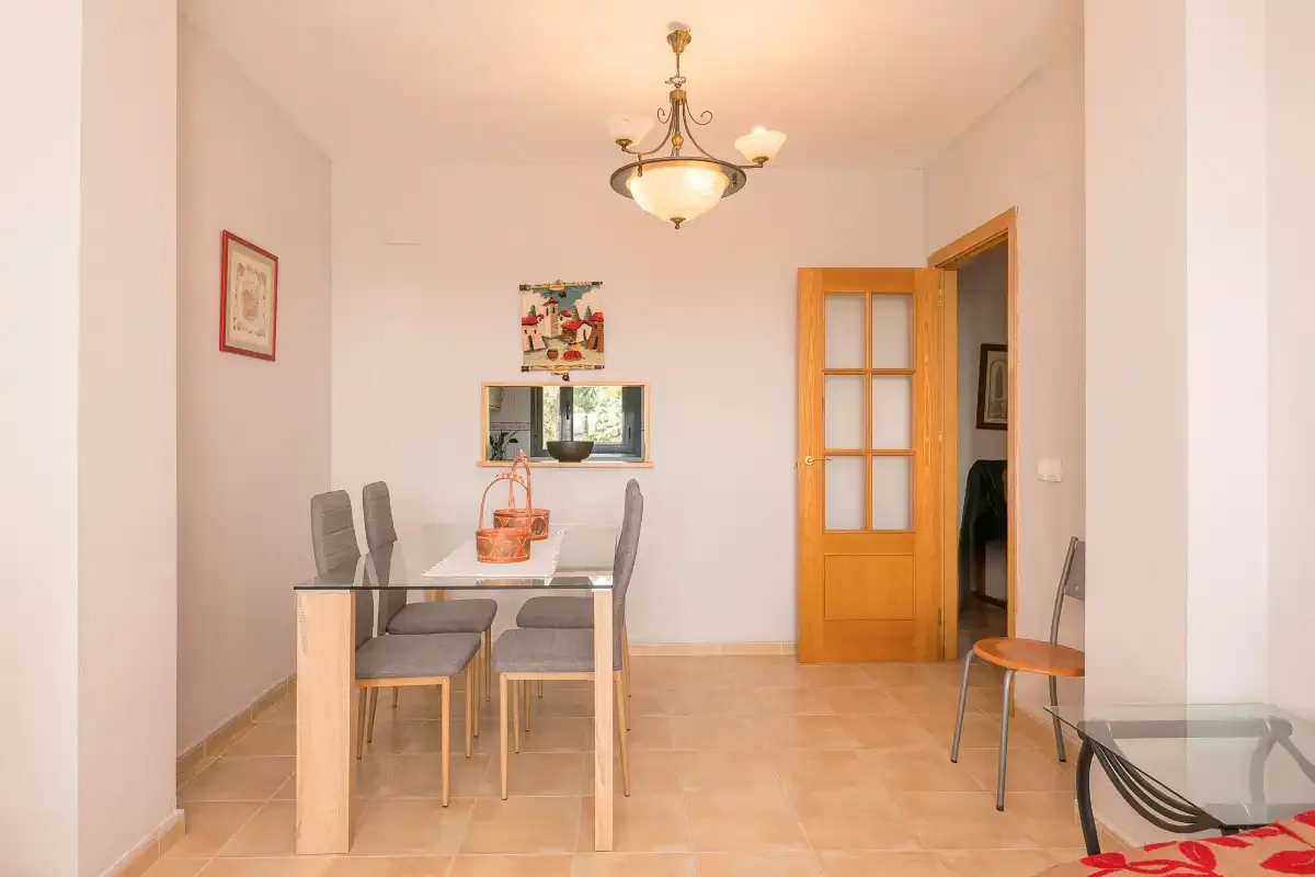 Comedor con una mesa y sillas junto a una puerta de madera abierta.