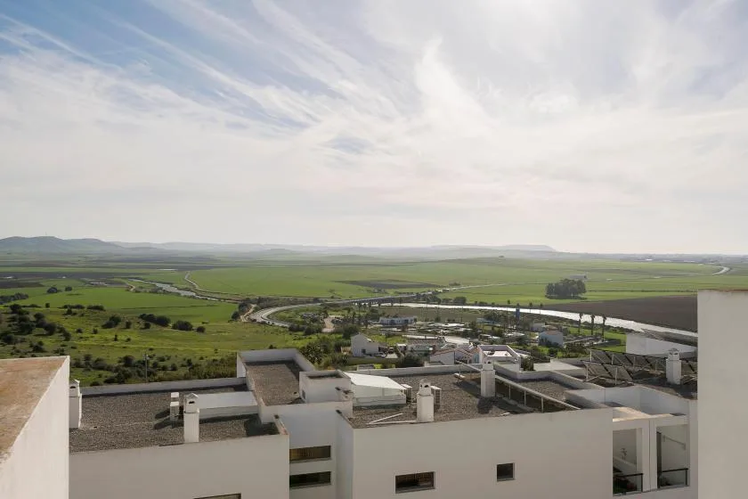 Desde una azotea se ven campos verdes bajo un cielo amplio y nublado.
