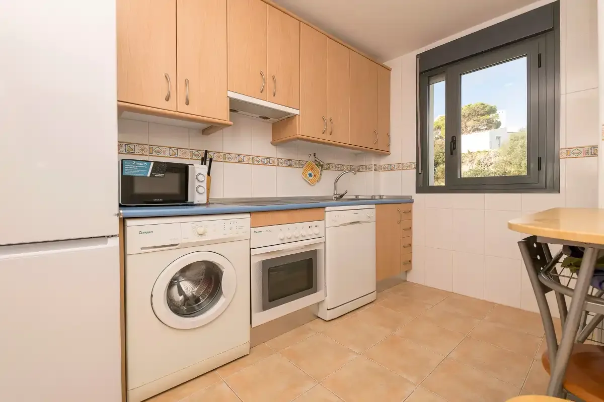 Una cocina con armarios de madera, electrodomésticos y una ventana.
