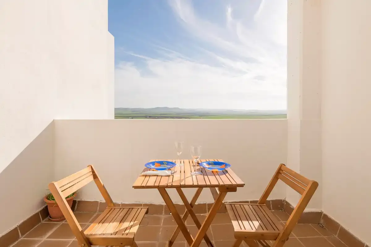 Una pequeña zona de comedor al aire libre con mesa y sillas de madera da al paisaje.