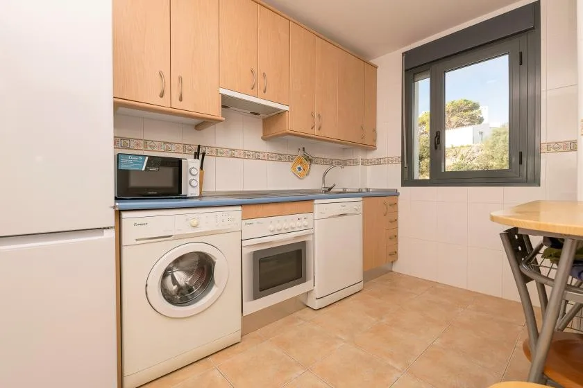 Una cocina luminosa con armarios de madera, electrodomésticos y una ventana.