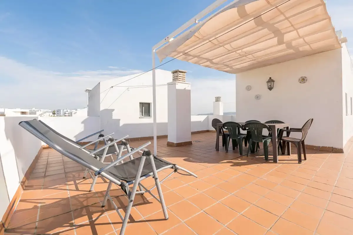 Una terraza soleada en la azotea con asientos al aire libre bajo un toldo.