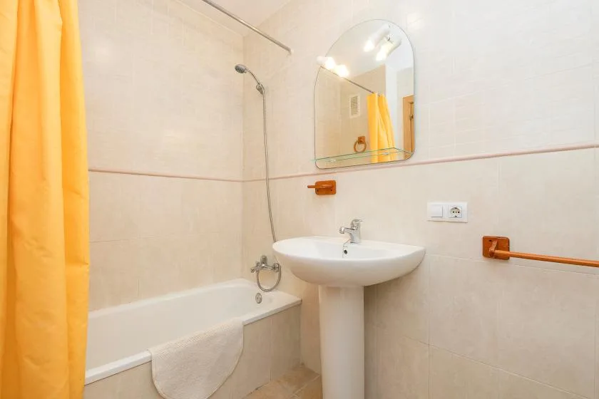 Un baño alicatado con bañera, lavabo y cortina de ducha amarilla.