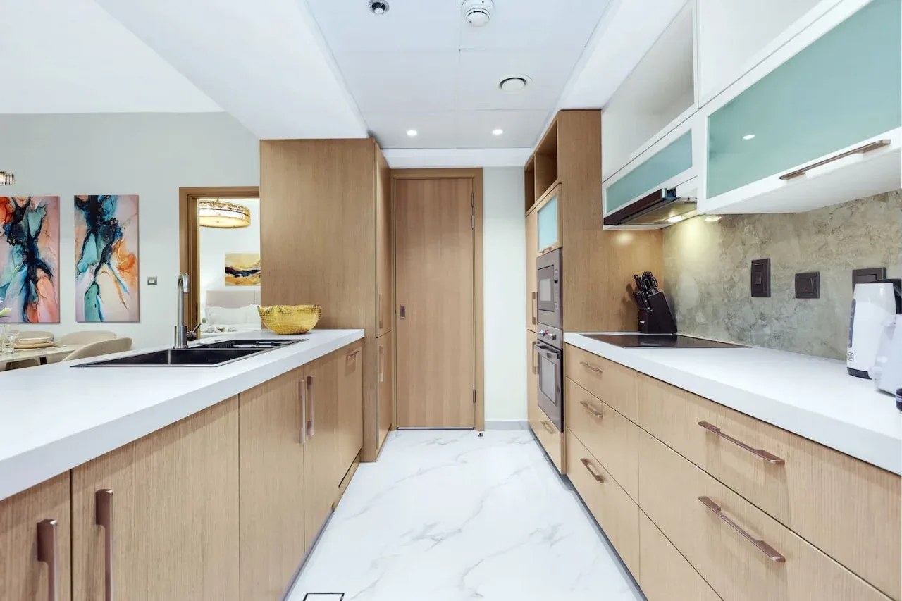 A modern kitchen with light wood cabinets and white countertops.