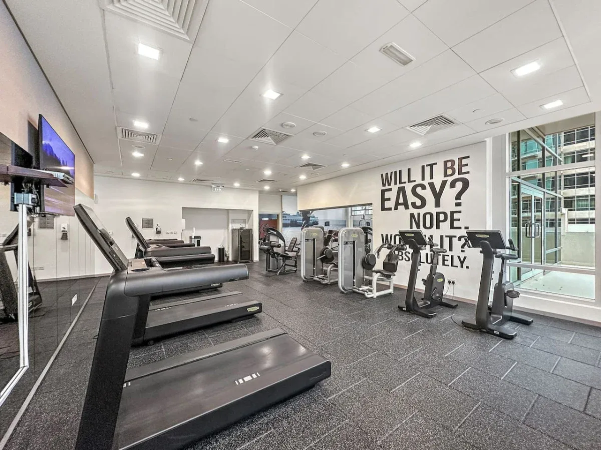 A gym with treadmills and exercise machines arranged across the room.