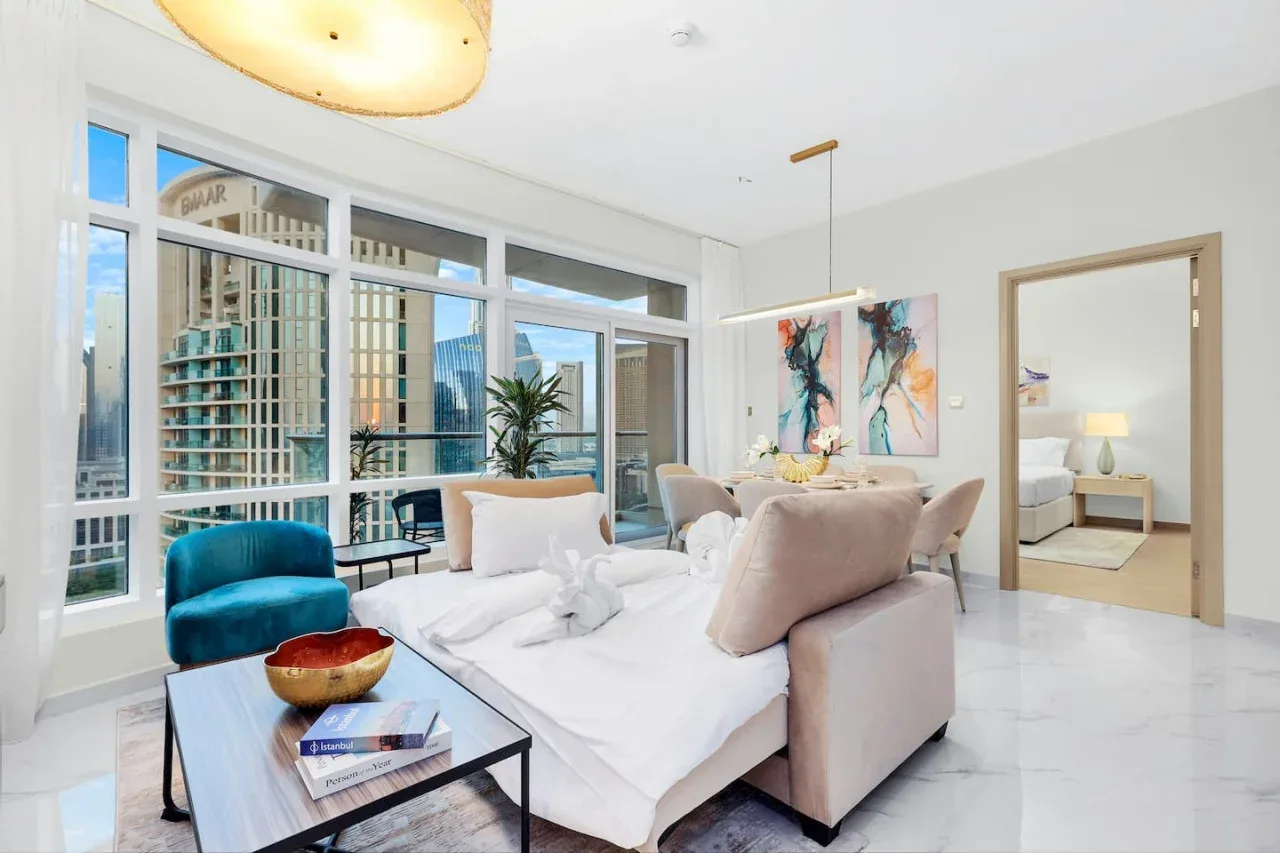 A bright living room with seating beside large windows and colorful wall art.