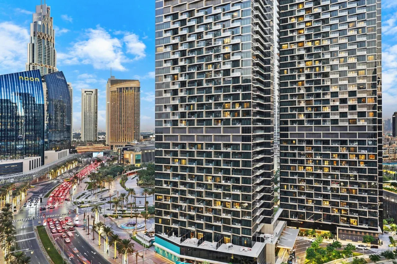 A city skyline with tall modern buildings beside a busy multi-lane road.