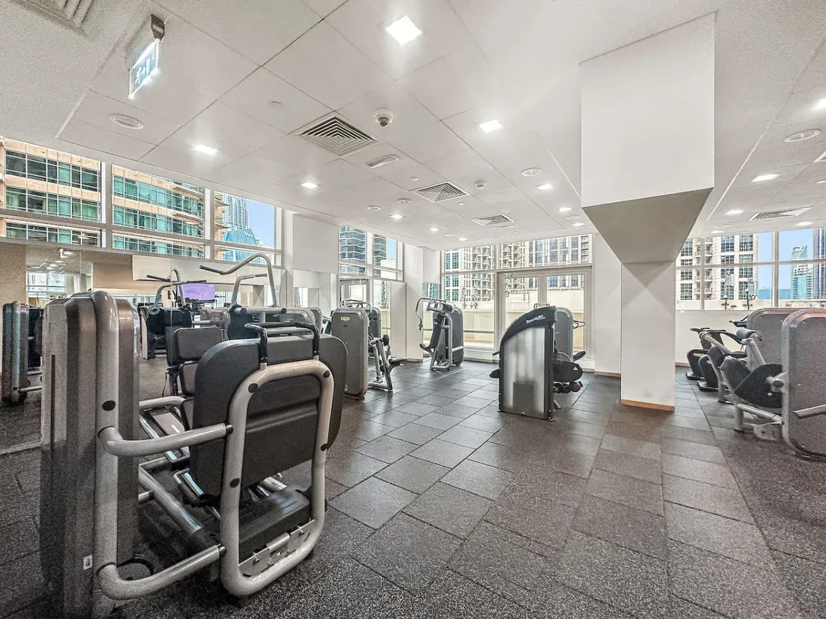 A bright gym with exercise machines arranged across a tiled floor.
