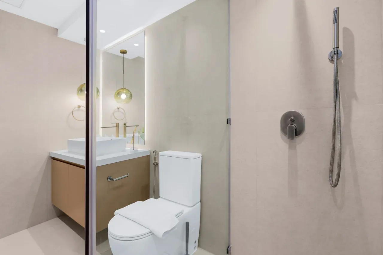 A modern bathroom with a sink, toilet, and wall-mounted shower.