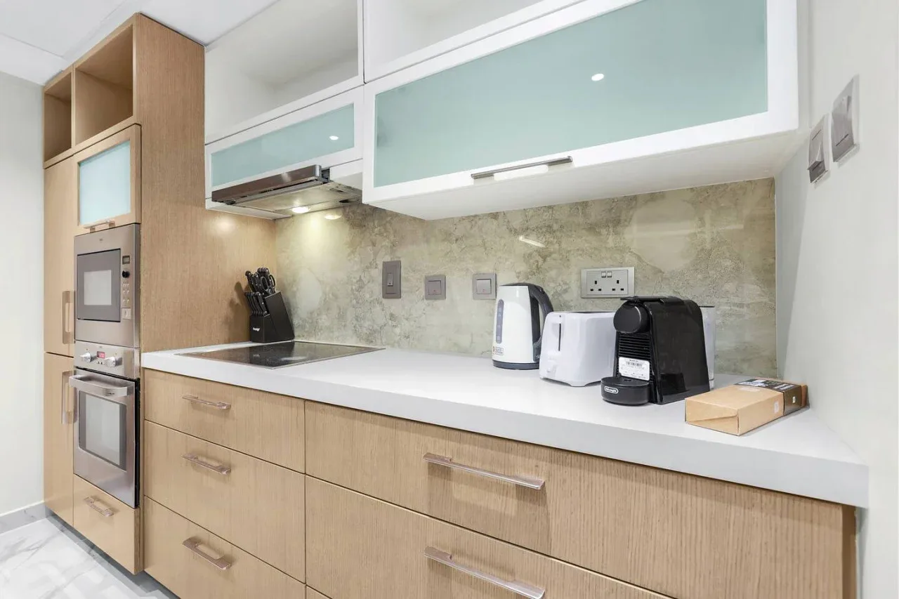 A modern kitchen with light wood cabinets and small appliances on the counter.