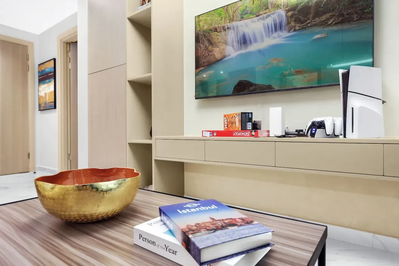 A living room with a low table, shelving, and a large landscape painting.
