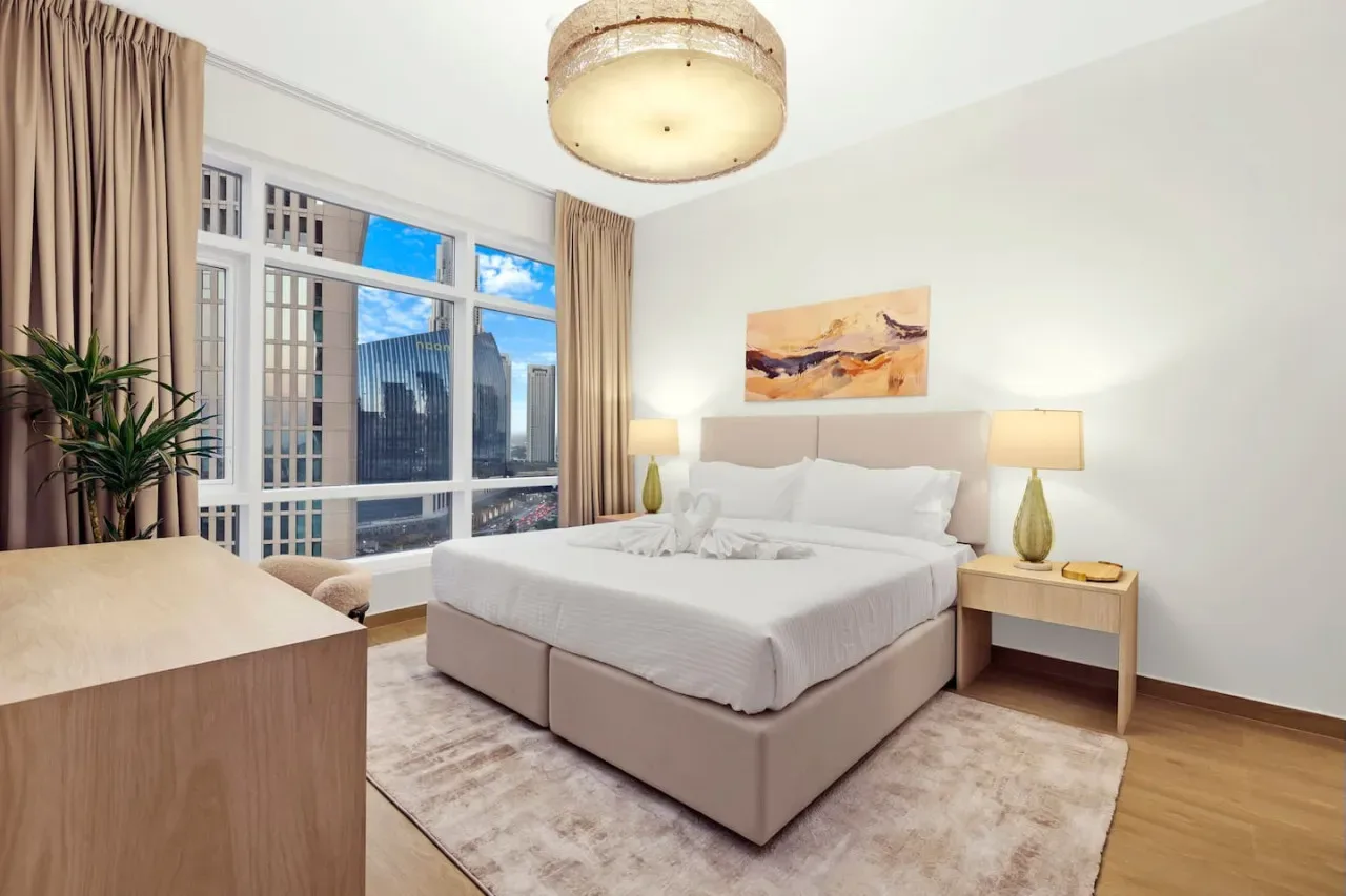A bedroom with a large bed, bedside tables, and tall windows.