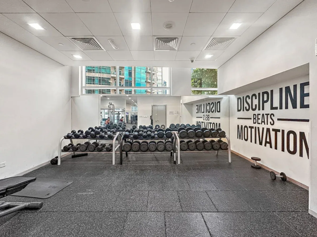 A gym with rows of dumbbells in front of a mirrored wall.
