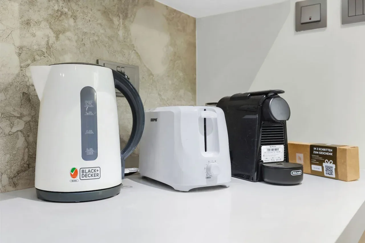 A kitchen counter holds a kettle, toaster, and coffee machine.