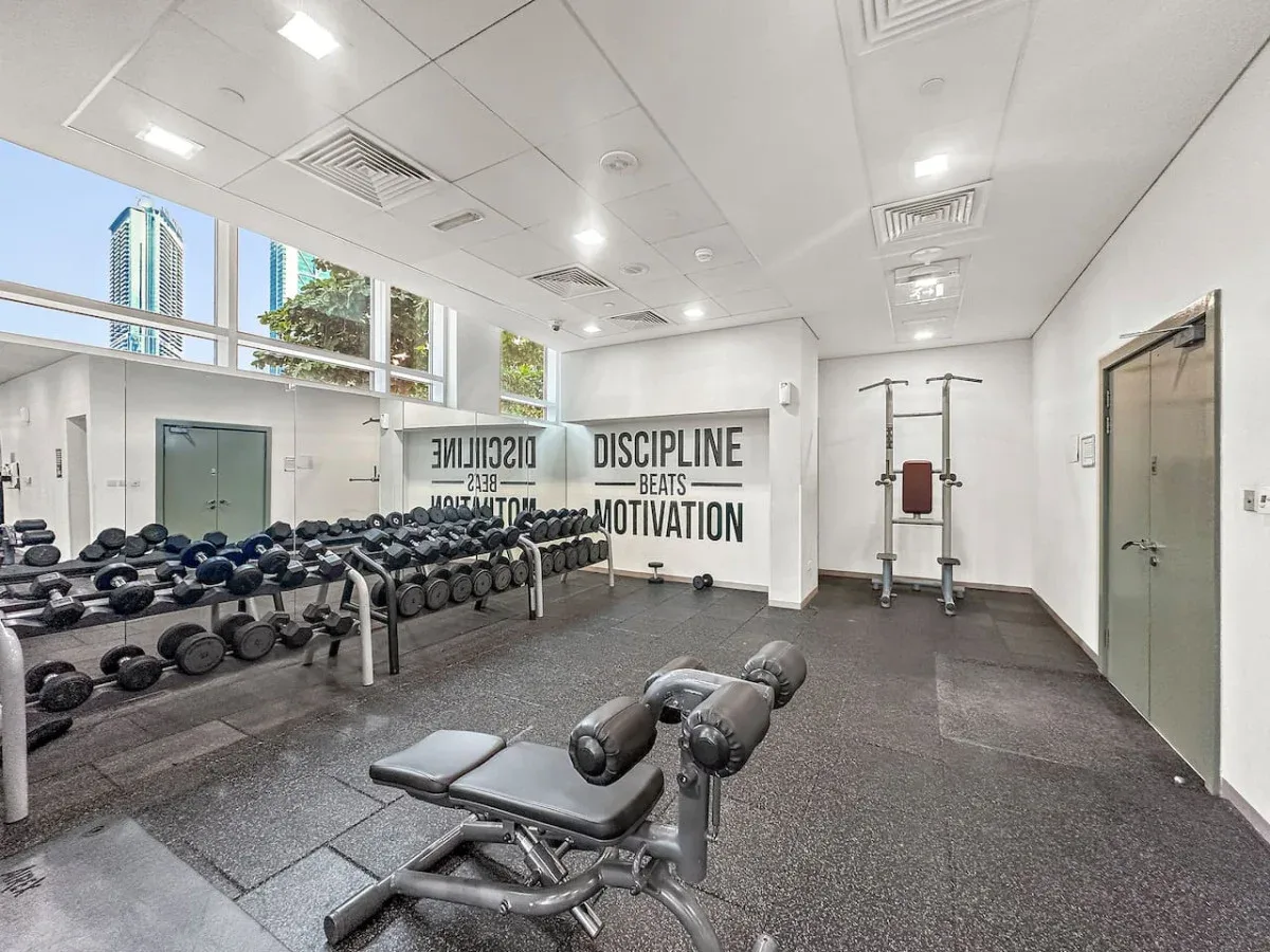 A gym with rows of dumbbells and a workout bench.