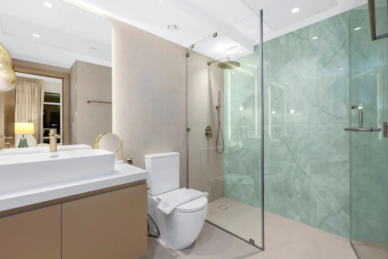 A modern bathroom with a vanity, toilet, and glass shower.