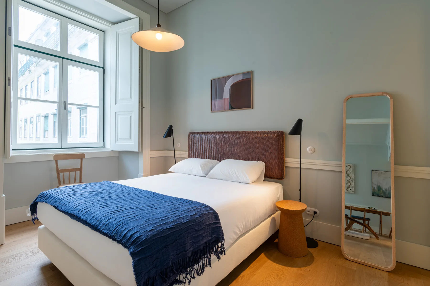 Un dormitorio con una cama bien hecha junto a una ventana grande.