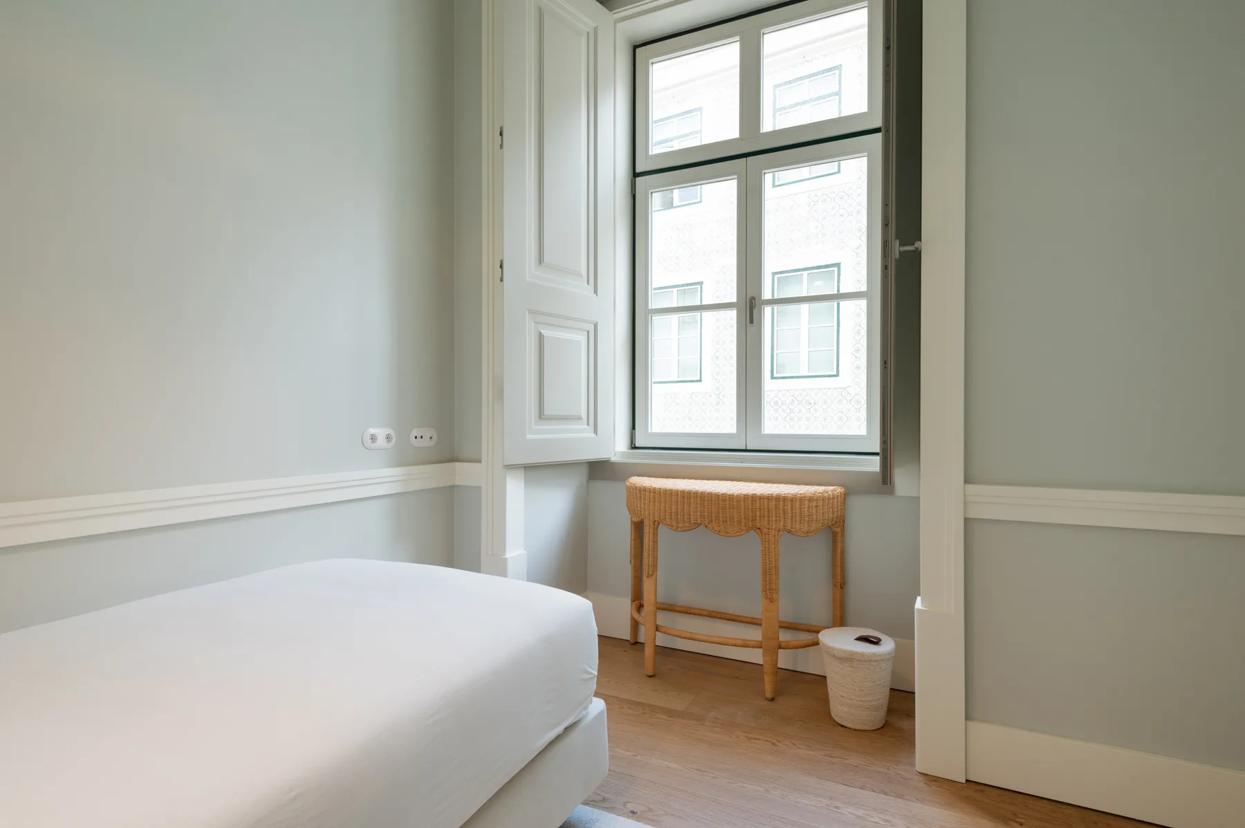 Un dormitorio luminoso con una cama junto a una ventana grande.